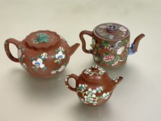 A group of three Chinese Yixing teapots, each with enamel painted decoration, comprising: a