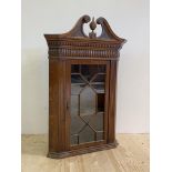 A George III oak hanging corner cabinet, late 18th century, the swan neck pediment with turned