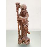 A Chinese hardwood carving of a sage, modelled carrying a staff. 37cm