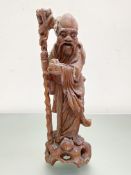 A Chinese hardwood carving of a sage, modelled carrying a staff. 37cm