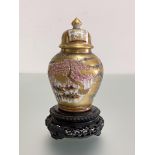 A small Japanese Satsuma baluster jar and cover, painted with figures in pavilions against a gilt-