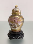 A small Japanese Satsuma baluster jar and cover, painted with figures in pavilions against a gilt-