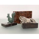 Two sculptural paperweights comprising: a silvered metal model of a sleeping lion after Canova,