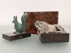 Two sculptural paperweights comprising: a silvered metal model of a sleeping lion after Canova,