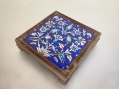 An Iznik pottery tile, painted with carnations, tulips and other flowers against a blue ground,