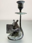 A patinated bronze novelty candlestick, modelled as a mouse reading a book, it's tail continuing
