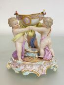 A 19th century Meissen porcelain figural salt, modelled as three putti holding a bowl with mask