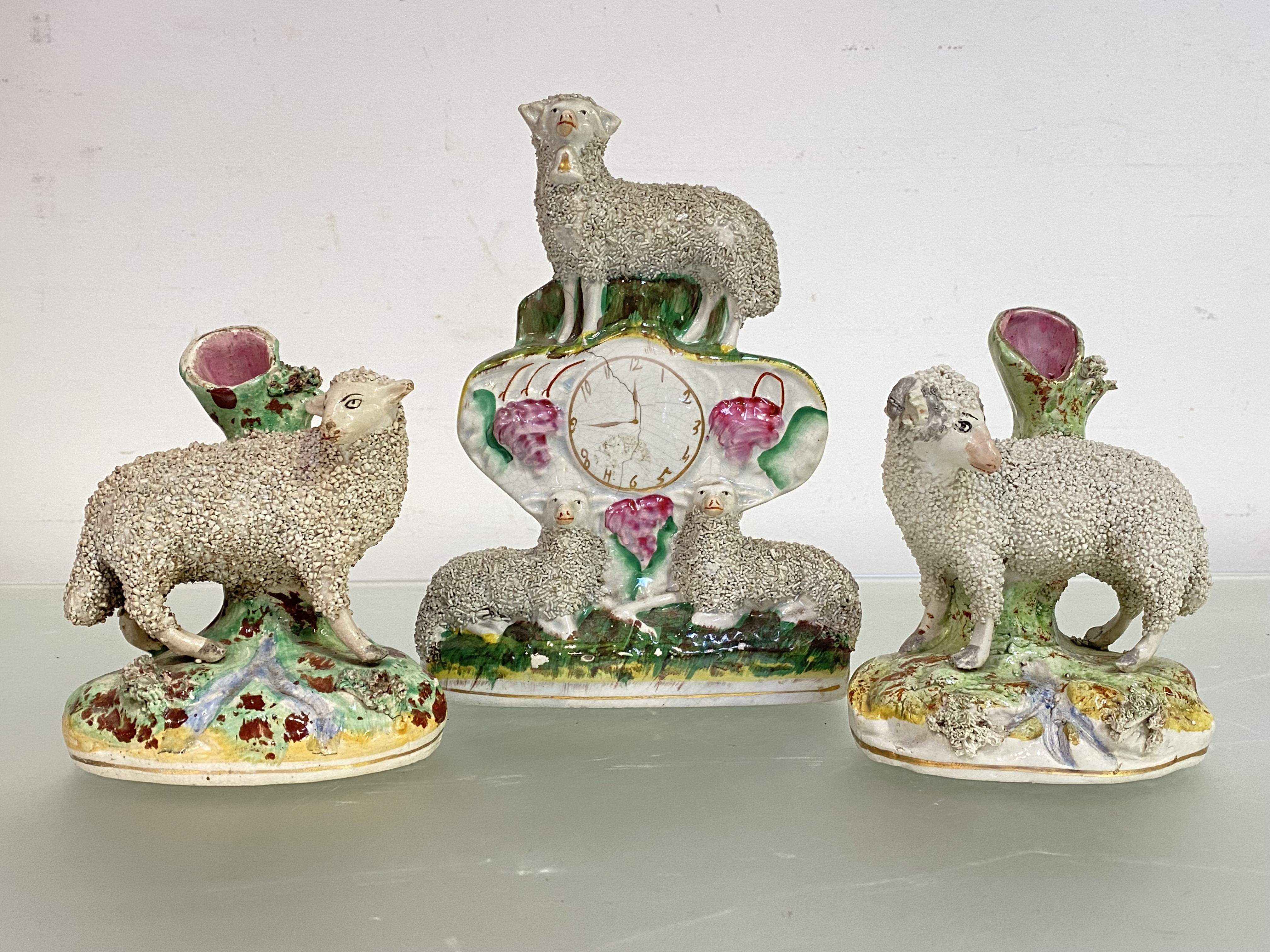 An assembled 19th century Staffordshire sheep model garniture of "clock" and pair of spill vases,