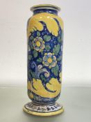 A large maiolica jar, of cylindrical form, boldly painted with flowers and leaves on a circular foot