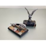 Two white metal car mascots, mounted as paperweights comprising: an eagle with outspread wings on