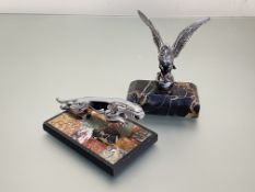 Two white metal car mascots, mounted as paperweights comprising: an eagle with outspread wings on