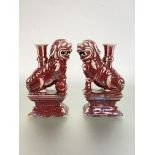 A pair of Chinese pottery incense burners modelled as lion dogs, in a sang de boeuf or oxblood