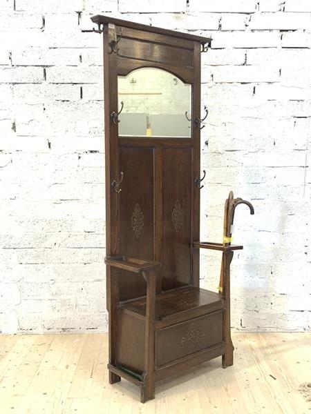 An early 20th century oak hall stand, the panelled mirror back with seven coat hooks over two