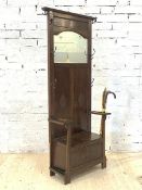 An early 20th century oak hall stand, the panelled mirror back with seven coat hooks over two