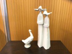 A Lladro figural group of two nuns measures 33cm high and a Nao figure of a duck (2)