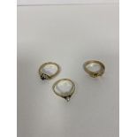 A group of three 9ct gold rings one with pearl flanked by three blue stones another with blue
