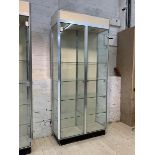 A modern glazed shop show case, the two doors enclosing four shelves, raised on an ebonised base,