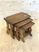 An elm nest of three tables, the rectangular tops raised on pierced panel end supports, H42cm,