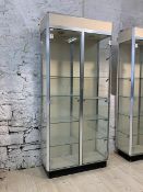 A modern glazed shop showcase, with two doors enclosing four shelves, on an ebonised base, H219cm,