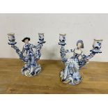 A pair of Dresden 20thc candlesticks each with a figure flanked by two candle holders both with