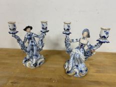 A pair of Dresden 20thc candlesticks each with a figure flanked by two candle holders both with
