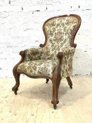 A mid Victorian mahogany framed balloon back armchair, upholstered in a floral fabric, with scrolled