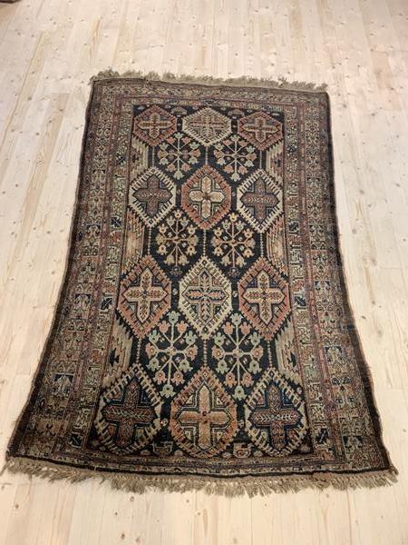 A Hand knotted tribal rug, the dark field with repeating lozenges and bordered, 149cm x 245cm