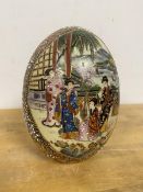 A Satsuma egg shaped table ornament with two panels depicting women on veranda playing instruments
