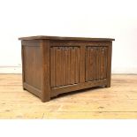 An oak blanket box, the hinged lid over two panel linen fold carved front, raised on stile