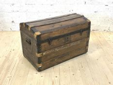 An early 20th century dome top steamer trunk, the hinged lid revealing plain interior, with carry