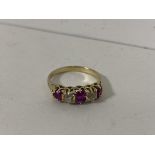 A yellow metal ring with three old cut rubies separated by diamonds size Q/R