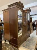 A Late 19th century mahogany triple wardrobe, the twin pediments with boxwood paterae over dentil