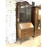 An early 20th century mahogany bureau bookcase, the arched top over two glazed doors enclosing three