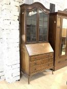 An early 20th century mahogany bureau bookcase, the arched top over two glazed doors enclosing three