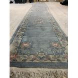 A large Chinese washed wool runner rug, the blue field with three medallions enclosed by a floral