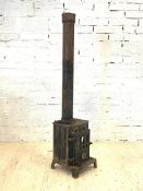 A cast iron log burning stove and flue, H177cm, W39cm, D44cm