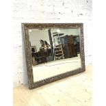A large wall hanging mirror, the silvered floral moulded frame enclosing a bevelled plate, 111cm x