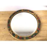 An Edwardian circular mirror with bevelled glass with a gilt and polychrome fruit and vine frame
