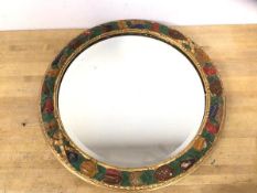 An Edwardian circular mirror with bevelled glass with a gilt and polychrome fruit and vine frame