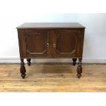 An early 20th century oak side cabinet, the moulded rectangular top over over two panelled doors,