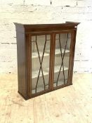 An Edwardian inlaid mahogany bookcase, the projecting cornice over two astragal glazed doors