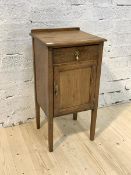 An early 20th century oak bedside table, with single drawer and cupboard, raised on square section