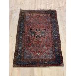 A hand knotted Tribal Persian rug, the abrashed red field with stylized foliate within a guarded