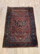 A hand knotted Tribal Persian rug, the abrashed red field with stylized foliate within a guarded