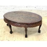 A Chinese hardwood oval coffee table, the plate glass top over figures carved with in a naturalistic