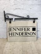A Scrolled wrought iron shop sign bracket, with sign reading Jennifer Henderson bracket measures