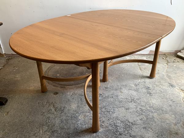 Ercol, A blonde extending dining table, the oval top with two additional leaves raised on turned and