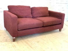 A modern two seat sofa, upholstered in purple fabric, raised on square tapered supports, H65cm,