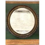 A 20th century oval wall hanging mirror, the bevelled plate within a conforming moulded frame,