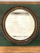 A 20th century oval wall hanging mirror, the bevelled plate within a conforming moulded frame,